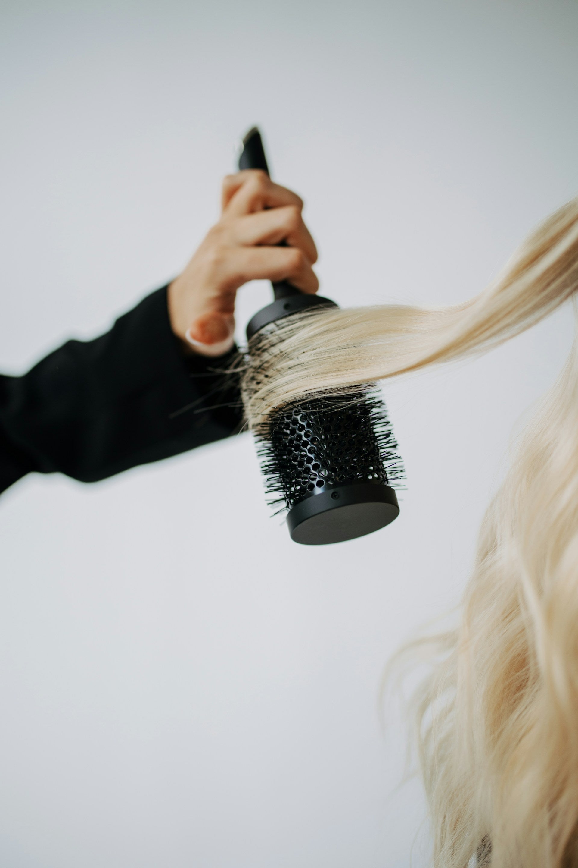 Close up of hand blowdrying and curling blonde hair