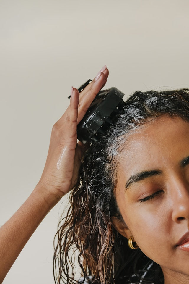 Woman massages her hair with hydrating shampoo and shampoo brush